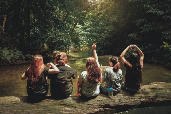 Girls in diverse body sizes sit together on a log