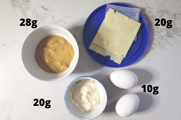 various foods representing an example of daily fat intake: 4 tablespoons PB, 2 slices cheese, 2 eggs, 2 tablespoons mayo dressing = 78 grams